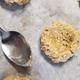 Using the back of a spoon to flatten the tops of the unbaked cookies